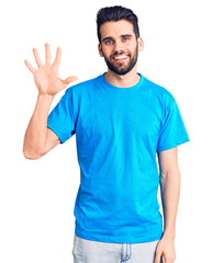 Fototapeta premium Young handsome man with beard wearing casual t-shirt showing and pointing up with fingers number five while smiling confident and happy.