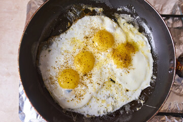 Four eggs are fried in a black pan