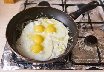 Four eggs are fried in a black pan
