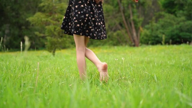 Unrecognizable young child walking on the grass barefoot. Concept of freedom and enjoying one s life. Tracking real time 4k