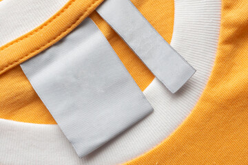 Blank white laundry care clothes label on yellow fabric texture background