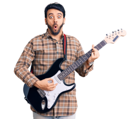 Young hispanic man playing electric guitar scared and amazed with open mouth for surprise, disbelief face