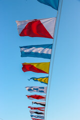 Naklejka premium Saint-Petersburg, Russia. International maritime signal flags are waving on wind under blue cloudy sky.