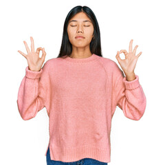 Beautiful young asian woman wearing casual winter sweater relax and smiling with eyes closed doing meditation gesture with fingers. yoga concept.