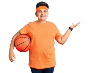 Little boy kid holding basketball ball celebrating victory with happy smile and winner expression with raised hands