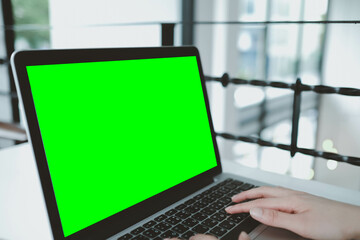 asian young businessman working on laptop with blank green screen in coffee shop.