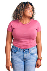 Young african american plus size woman wearing casual clothes looking away to side with smile on face, natural expression. laughing confident.