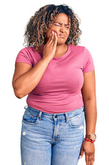 Young african american plus size woman wearing casual clothes touching mouth with hand with painful expression because of toothache or dental illness on teeth. dentist