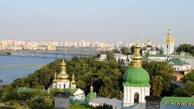 Kyiv Pechersk Lavra cupola. Kiev summer landscape with Dnieper river and bridge in sunny day and blue sky with white clouds, Europe travel diversity