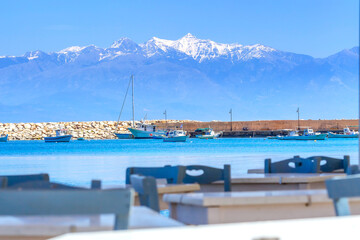 Fototapeta na wymiar Sea, boats and snow mountains in Peloponnese, Greece