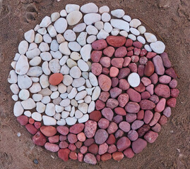 Yin and yang symbol created with stones and pebbles, sand texture background. Baltic sea shore, Saaremaa, Estonia. Japanese rock garden, culture and religion, relaxation, meditation, peace concepts