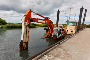 Submerged dredging excavator crane and boat in a river. Industry, special equipment,...