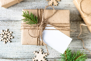 Christmas present with white blank mockup tag and fir tree branches on white background.