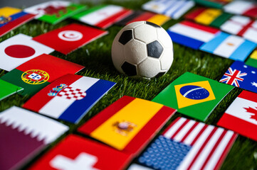 Fototapeta Soccer Wallpaper. Football Ball on green Grass and 32 Flags which will play in Qatar on December 2022 obraz