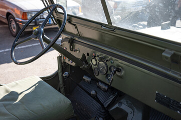Detail of an old green military SUV. Interior view, steering wheel and controls