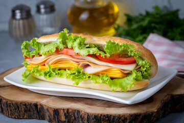 Cheese, ham, lettuce and tomato slices in an appetizing tasty sandwich.