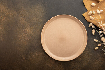 Table setting, empty plate and cutlery on a brown background, top view of the served table...