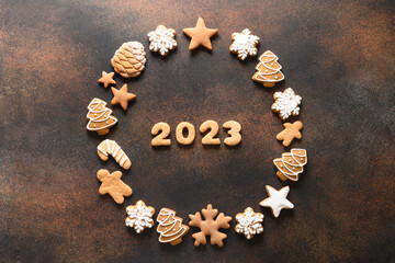 Christmas wreath of assorted glazed cookies with date 2023 inside on brown background. New Year...