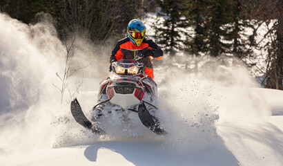 Snowmobile riding with fun in deep snow powder during backcountry tour. Extreme sport adventure,...