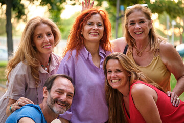 Portrait of five mature adults taking a selfie and having fun in a park.