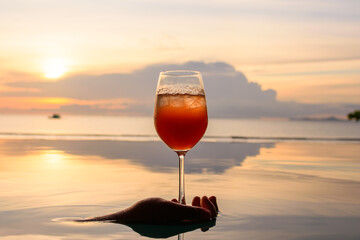A cocktail in the wine glass over swimming pool. Beautiful scene reflection water.