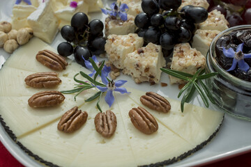selection  of cheeses with grapes and edible flowers