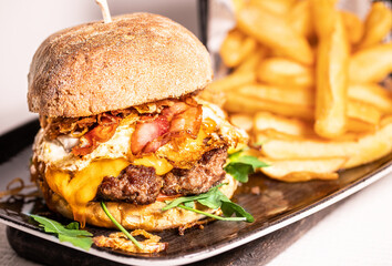 Homemade spicy hot cheeseburger with grilled beef, cheese and lettuce leaf between burger buns, side view, restaurant concept