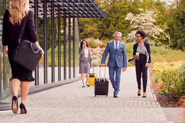 Group Of Business Delegates With Luggage Arriving At Conference Hotel