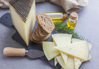 Queso manchego cortado en lonchas y apilado sobre un plato con pan y aceite de oliva