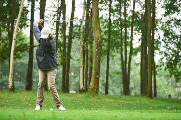 woman with cap playing golf under rain