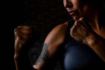 I'm an athlete concept lifestyle. Close up of woman in boxe pose. Black background and shadow,...