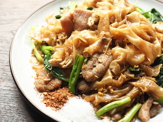 Pad See Ew, Thai stir fried noodles with dark soy sauce, served with sugar and chili flakes