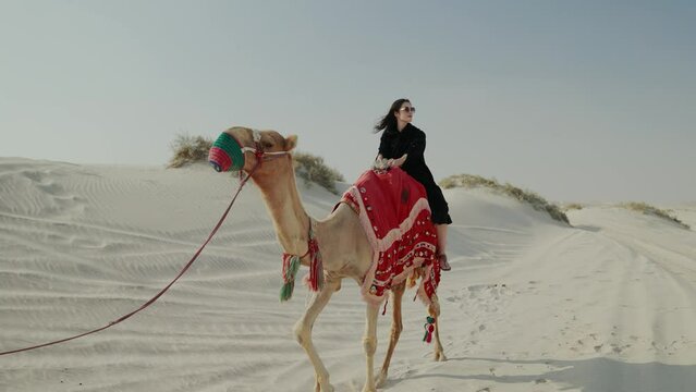 tourist woman riding camel with cameleer leading
