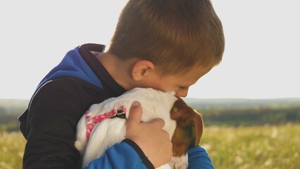 happy family. little boy kisses dog. toddler boy holds beloved pet his arms smiles. since...