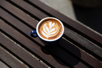 cup of cappuccino with latte art on wooden background