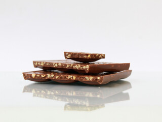 Pieces of milk chocolate with nuts isolated on white  background with reflection