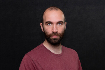 Portrait of a serious man 30-35 years old in a T-shirt on a black background.