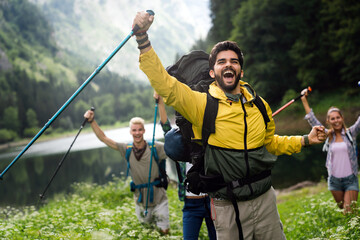 Group of smiling friends hiking with backpacks outdoors. Travel, tourism, hike and people concept.
