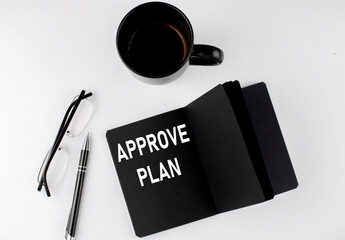 Naklejka premium APPROVE PLAN written text in small black notebook with coffee , pen and glasess on white background. Black-white style