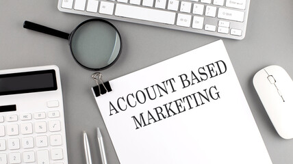 ACCOUNT BASED MARKETING written on paper with office tools and keyboard on the grey background