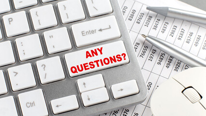 ANY QUESTIONS text on a keyboard wirh chart and pencil