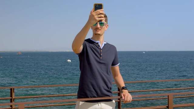 Man taking a picture of himself in front of the mediterranean coastline in Southern France.