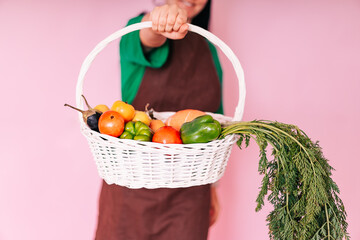 a young farmer girl holds a basket of vegetables just picked from the garden on her outstretched hand. the concept of harvesting