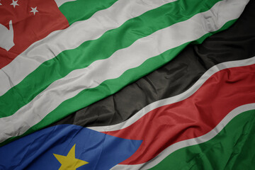 waving colorful flag of south sudan and national flag of abkhazia.