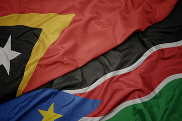 waving colorful flag of south sudan and national flag of east timor.
