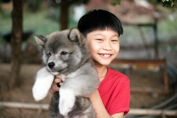 Happy little asian boy holding dog at home