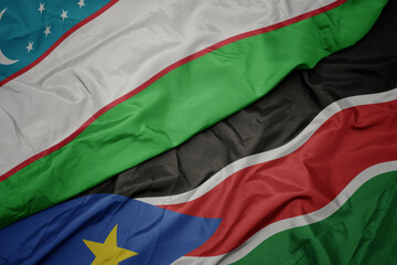 waving colorful flag of south sudan and national flag of uzbekistan.