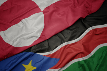 waving colorful flag of south sudan and national flag of greenland.