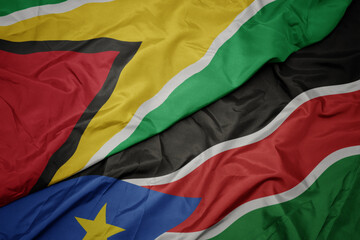 waving colorful flag of south sudan and national flag of guyana.