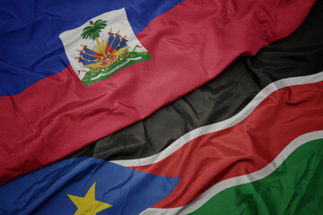 waving colorful flag of south sudan and national flag of haiti.